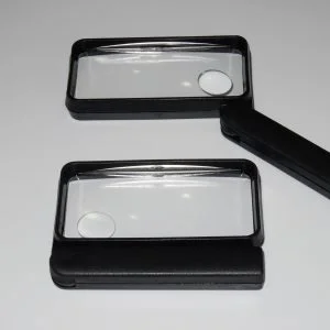 LUPA DE MÃO COM FORMATO RETANGULAR, NA COR PRETA, POSSUI NO MEIO DA LENTE UMA LUPA PEQUENA BIFOCAL, O DIÂMETRO DA LENTE É DE 100MM POR 50MM, CABO QUE ABRE E FECHA.