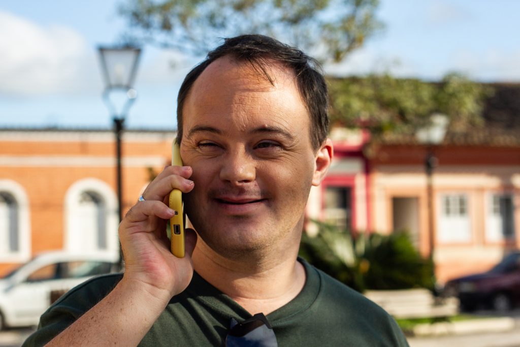 homem branco com síndrome de down conversando no telefone