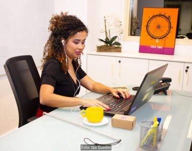 mulher negra digitando em um notebook, sentada em um escritório