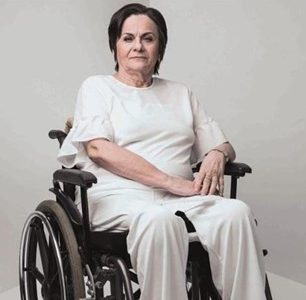 Mulher branca em cadeira de rodas com roupa branca em um fundo branco