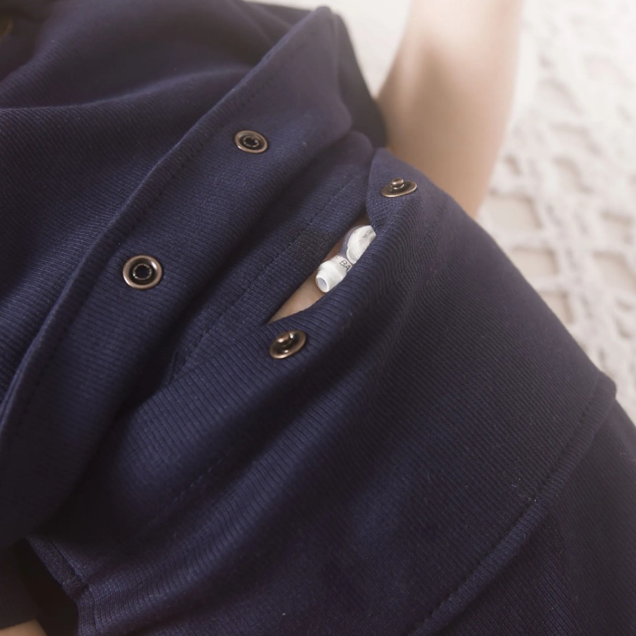 Menina usando um body manga curta na cor marinho com abertura escondida abaixo do bolso para acesso a gtt, facilitando a alimentação e abertura no ombro com botão