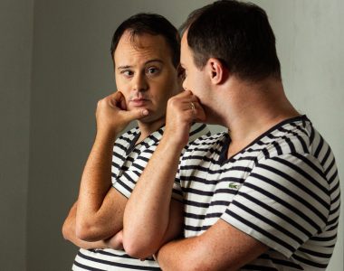 foto de homem de pele branca com síndrome de down se olhando no espelho